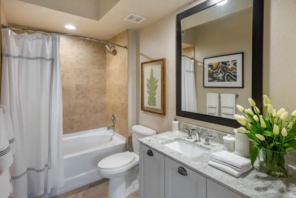 Bathroom with granite countertop, undermount sink large mirror, and bathtub shower