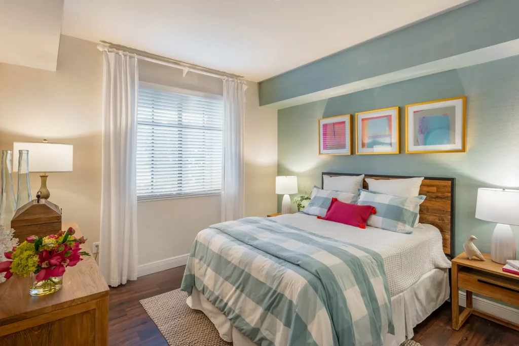 Bedroom with accent wall, wood style floors, and window