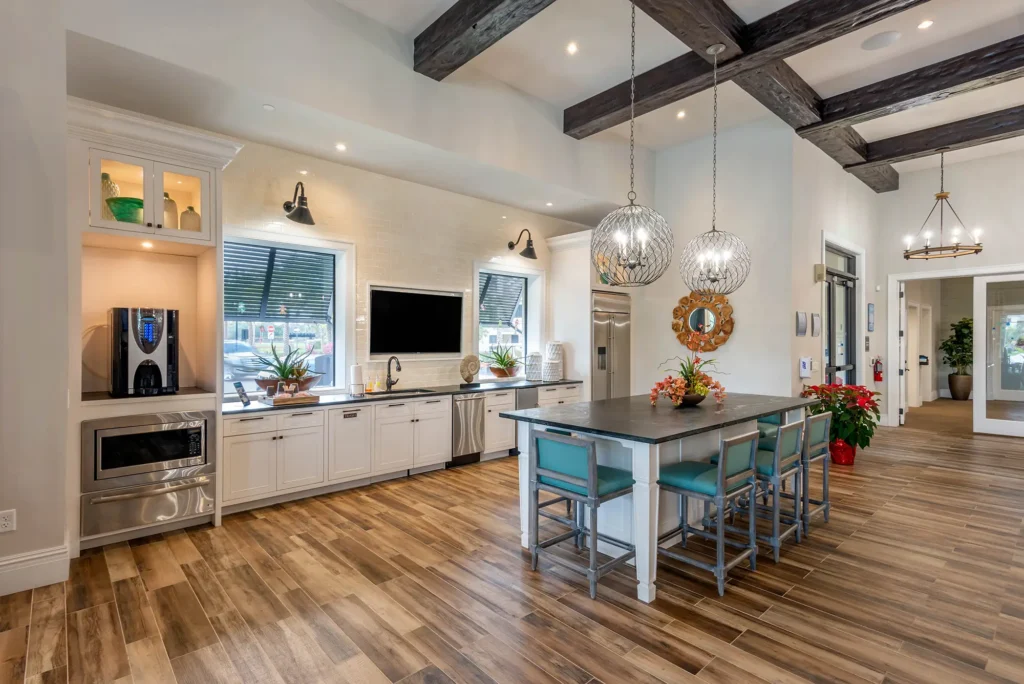Shared clubhouse kitchen with ample island seating, TV, sink, coffee machine, fridge, microwave, and dishwasher