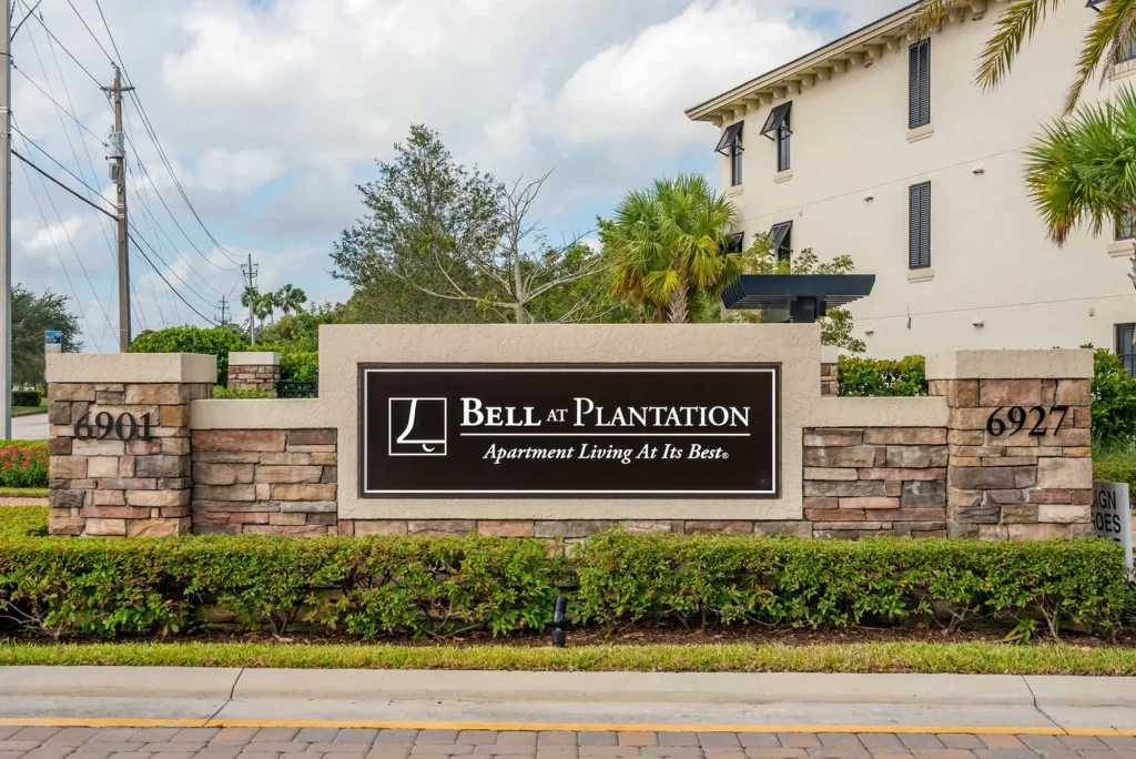 Bell at plantation sign outside building. Apartment living at its best. 6901, 6927.