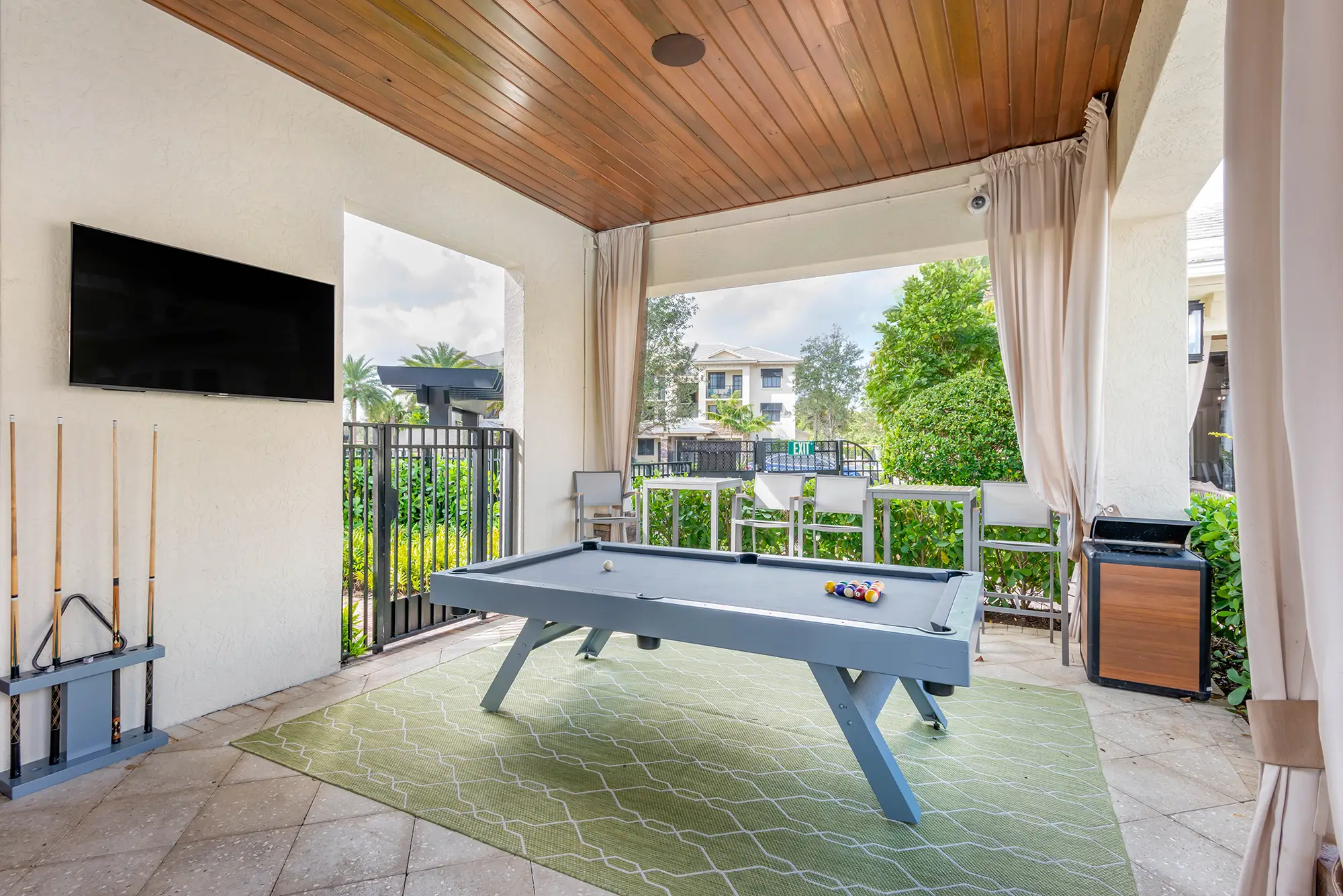 Covered patio with pool table and tv.
